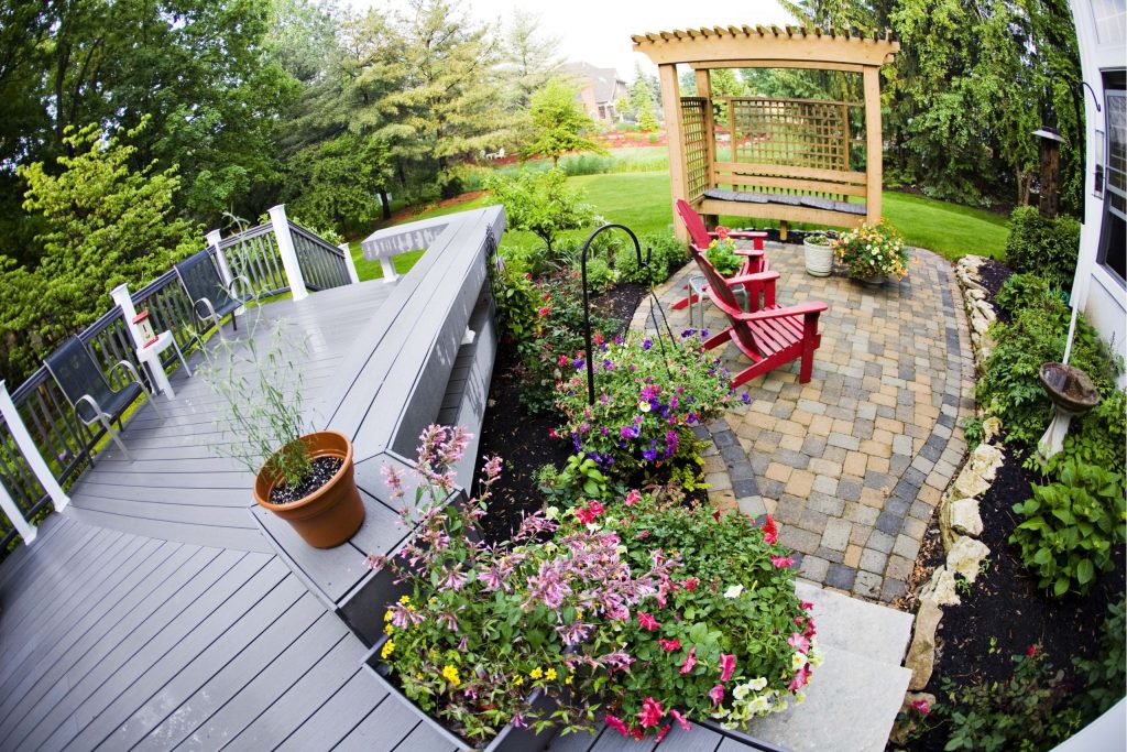 Composite decking ideas for small gardens includes using light colours, like grey decking and bright flowers