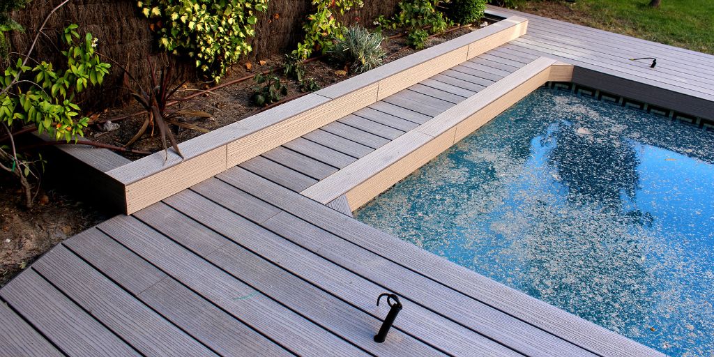 Composite decking surrounding a dirty pool in a back garden